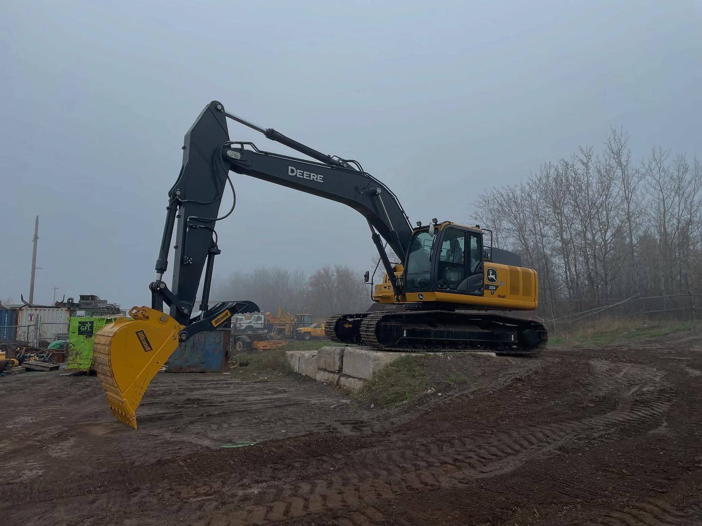 Superior Yard Works' new John Deere 250P excavator on a foggy Thunder Bay job site
