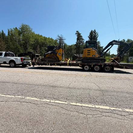 Truck and gooseneck hauling two John Deere machines