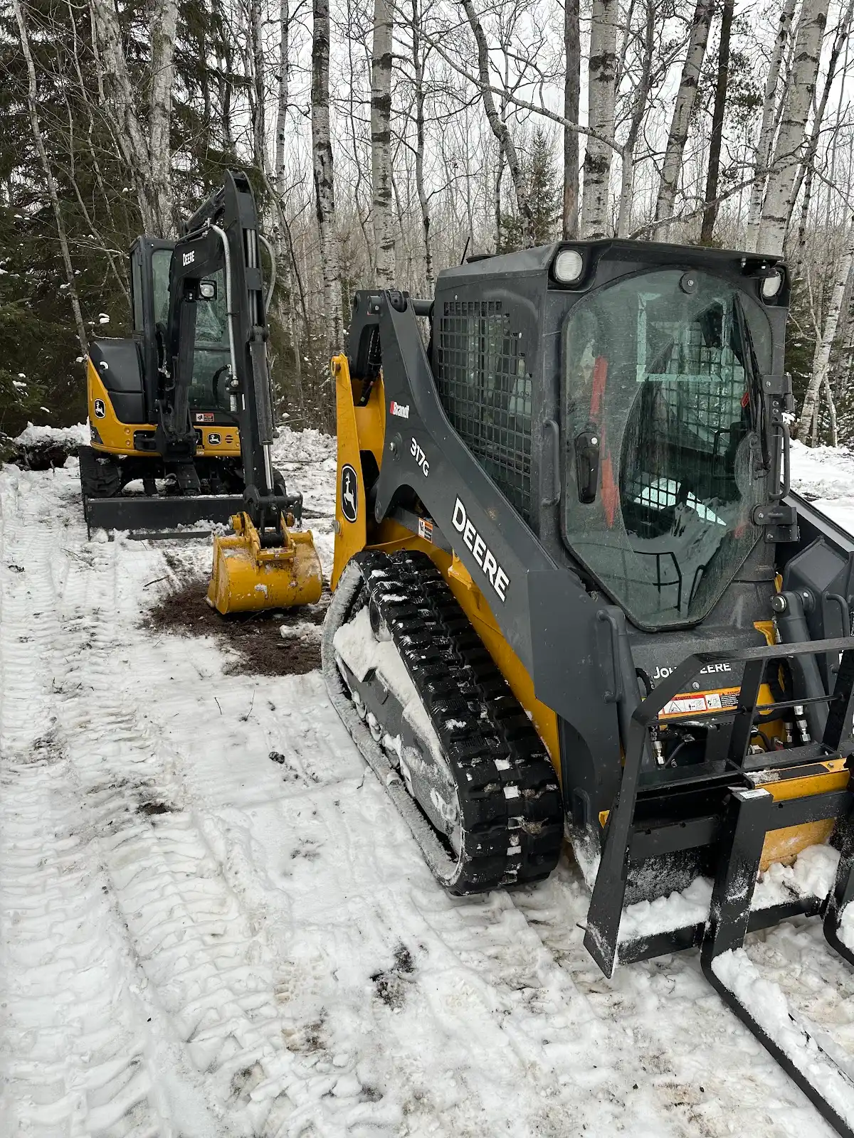 John Deere skid steer and excavator ready for winter work in the snow